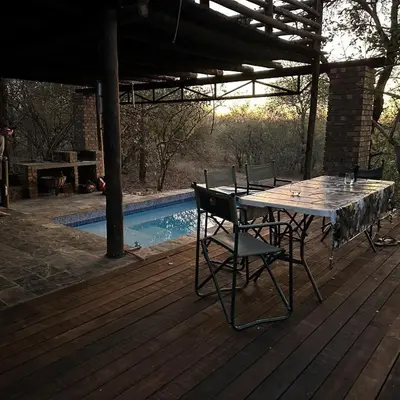 a wooden deck with a table and chairs next to a pool at Wabisabi the wild at your doorstep in Marloth Park
