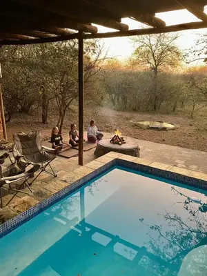 a group of people sitting around a swimming pool at Wabisabi the wild at your doorstep in Marloth Park