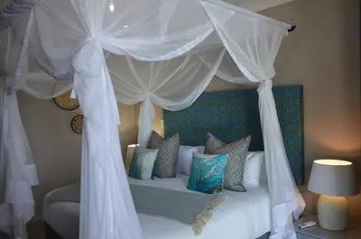 a bedroom with a canopy bed with white curtains and pillows at Ingwenkala Luxury Safari Lodge - 5 Star in Hoedspruit