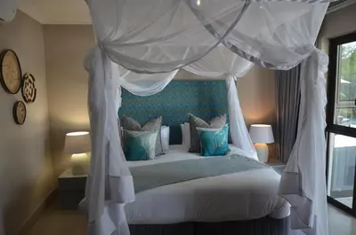 a bedroom with a canopy bed with blue pillows at Ingwenkala Luxury Safari Lodge - 5 Star in Hoedspruit