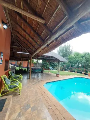 an outdoor patio with a swimming pool and a wooden ceiling at Coral Suite in Pretoria