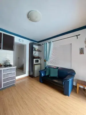 a living room with a blue couch and a kitchen at Coral Suite in Pretoria