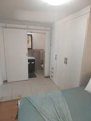 a bedroom with a bed and a bathroom with a kitchen at Coral Suite in Pretoria
