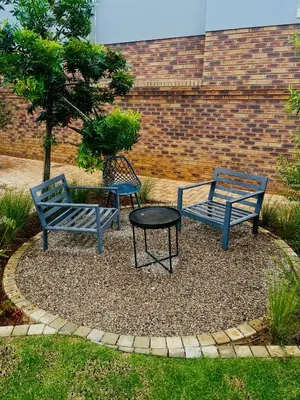 two blue benches and a table in front of a brick wall at Dimension 1 in Midrand