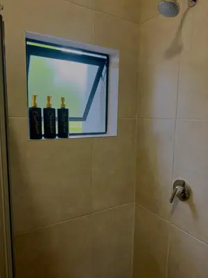 a bathroom with a shower with a window at Dimension 1 in Midrand