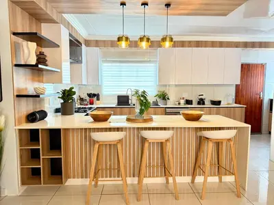 a kitchen with a large wooden island with bar stools at Luxury Redefined Home in Middelburg