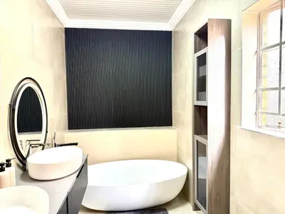 a bathroom with a large white tub and a sink at Luxury Redefined Home in Middelburg