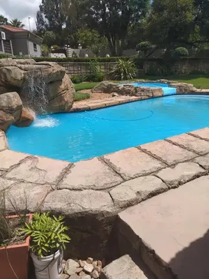 a swimming pool with a waterfall in a yard at The Adress Events Venue in Midrand