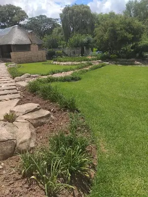 a garden with grass and rocks and a house at The Adress Events Venue in Midrand