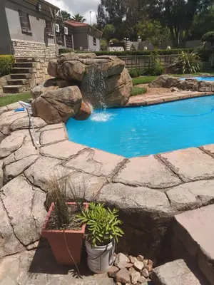 a swimming pool with a waterfall in a yard at The Adress Events Venue in Midrand