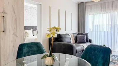 a living room with a glass table and blue chairs at Binbin Serenity Suite in Midrand