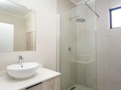 a white bathroom with a sink and a shower at Binbin Serenity Suite in Midrand