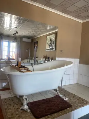 a large white tub in a bathroom with a sink at Mementos Guesthouse in Ga-Mapogo
