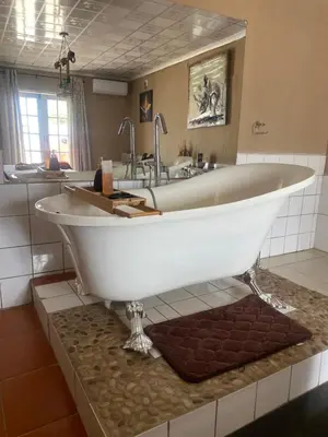 a large white tub in a bathroom with a sink at Mementos Guesthouse in Ga-Mapogo