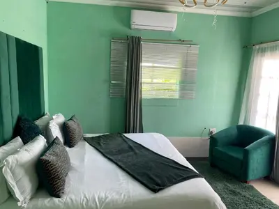a green bedroom with a bed and a chair at Mementos Guesthouse in Ga-Mapogo