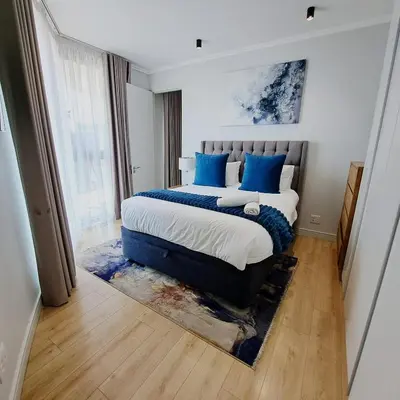 a bedroom with a large bed with blue pillows at Ellipse Waterfall luxurious and modern apartment in Midrand
