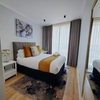 a bedroom with a large bed and some windows at Ellipse Waterfall luxurious and modern apartment in Midrand