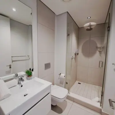 a bathroom with a sink and a toilet and a shower at Ellipse Waterfall luxurious and modern apartment in Midrand