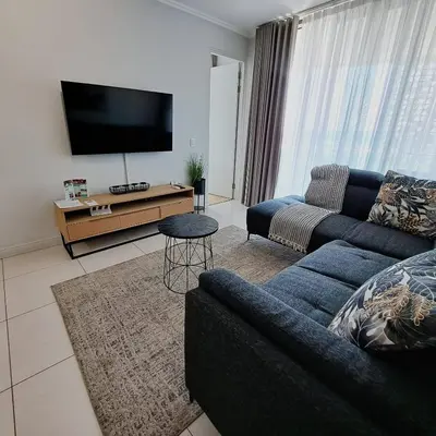 a living room with a couch and a flat screen tv at Ellipse Waterfall luxurious and modern apartment in Midrand