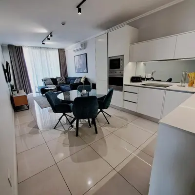 a kitchen and a living room with a table and chairs at Ellipse Waterfall luxurious and modern apartment in Midrand