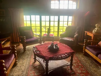 a living room with couches and a table and windows at Hermit Hill in Broederstroom