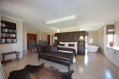 a bedroom with a bed and a couch and a bathroom at The Finches Nest in Hammanskraal
