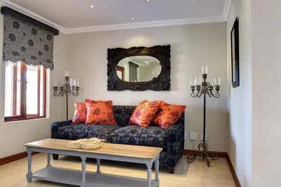 a living room with a couch and a mirror at The Finches Nest in Hammanskraal