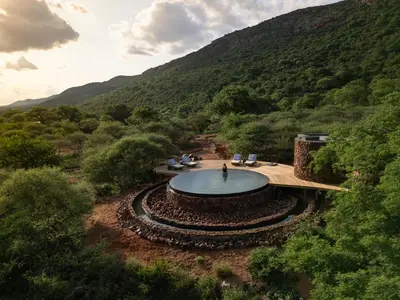 a person standing in front of a pool in the middle of a mountain at Few and Far Luvhondo in Waterpoort