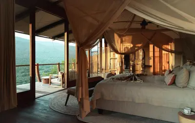 a bedroom with a bed and a balcony with a view at Few and Far Luvhondo in Waterpoort