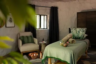 a bedroom with a bed and a chair and a window at Few and Far Luvhondo in Waterpoort