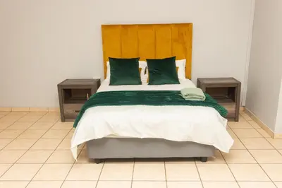 a bedroom with a large bed with green pillows at 22 Eland in Polokwane