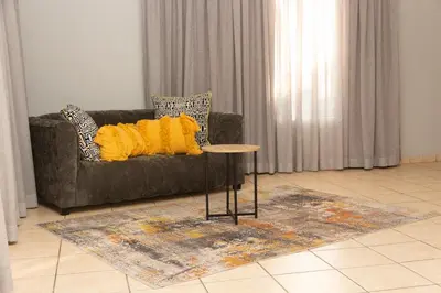 a couch with yellow pillows and a table in a living room at 22 Eland in Polokwane