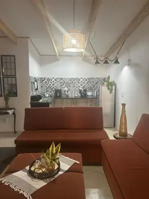 a living room with a brown couch and a kitchen at @144 Rabe in Mokopane