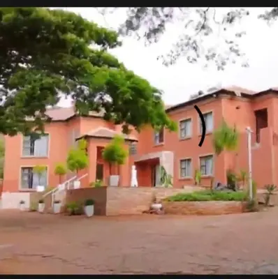 a large orange building with a tree in front of it at Mountvista Guesthouse in Pretoria