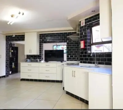 a kitchen with white cabinets and a black brick wall at Mountvista Guesthouse in Pretoria