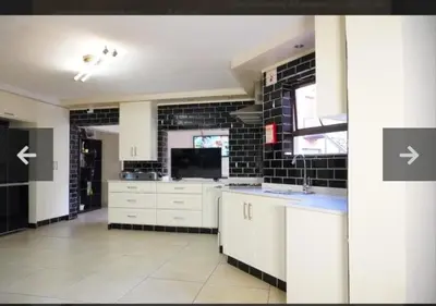 a kitchen with white cabinets and a black brick wall at Mountvista Guesthouse in Pretoria