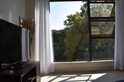 a living room with a television and a large window at Mountvista Guesthouse in Pretoria