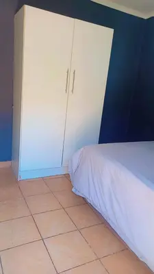 a bedroom with a white bed and a blue wall at comfort zone in Kempton Park