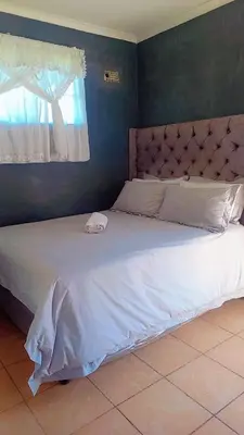 a large bed in a bedroom with a window at comfort zone in Kempton Park