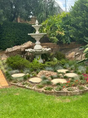 a fountain in a garden with grass and flowers at 943 on Jacques in Pretoria