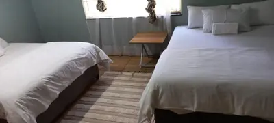 a bedroom with two beds and a wooden table at Majestic Guest House in Mokopane
