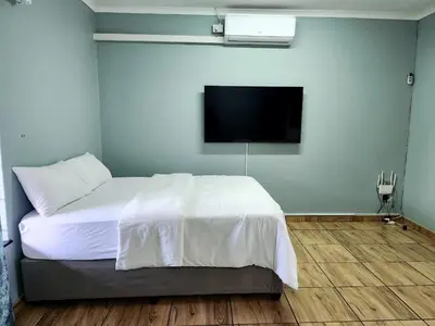 a bedroom with a bed and a flat screen tv at Majestic Guest House in Mokopane