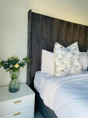 a bed with a wooden headboard and a vase of flowers at 1 bedroom- The Blyde by Given in Pretoria