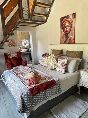 a bedroom with a large bed with a painting on the wall at casa bella in Hartbeespoort