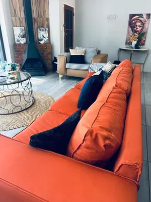 an orange couch with pillows in a living room at casa bella in Hartbeespoort