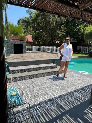 a woman in a white dress standing next to a swimming pool at casa bella in Hartbeespoort