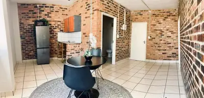 a kitchen with a table and a brick wall at Kwamathebula in Benoni