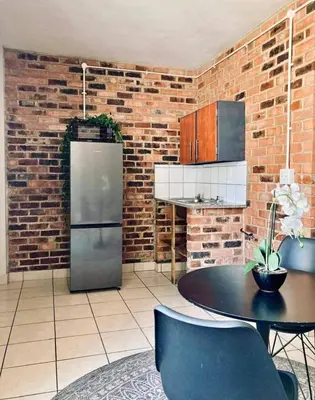 a kitchen with a refrigerator and a table with chairs at Kwamathebula in Benoni