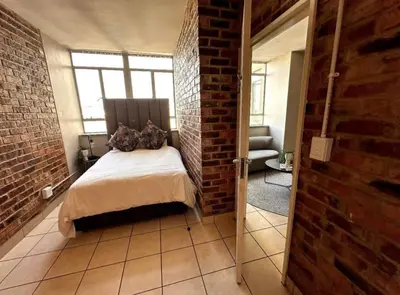 a bedroom with a bed and a brick wall at Kwamathebula in Benoni