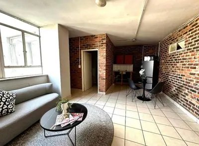 a living room with a couch and a brick wall at Kwamathebula in Benoni